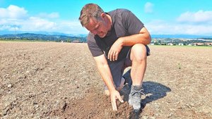 Christof Dähler kniet auf dem Feld und schaut sich das Ergebnis nach dem Geohobel an.