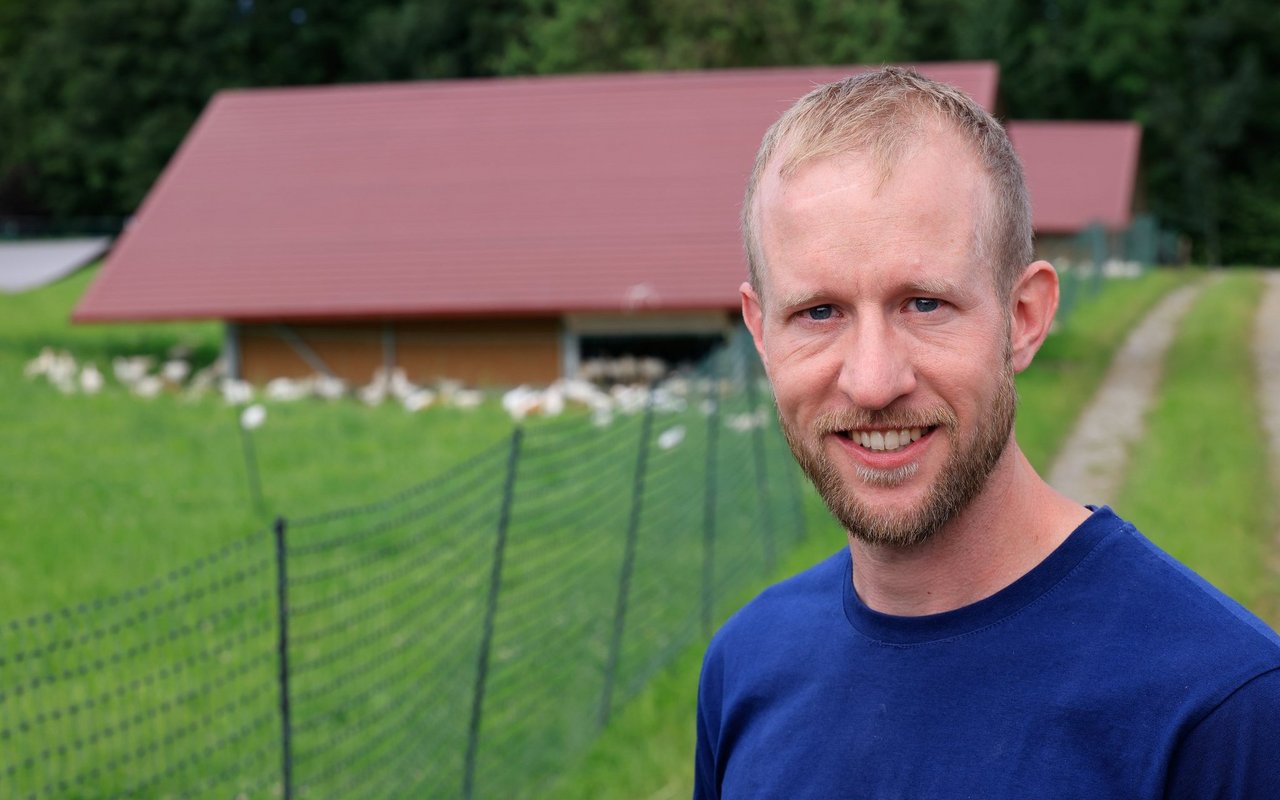 Philipp Müller steht vor der Weide seiner Hühner.